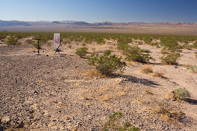 image of desert with sign, chair, and lecturn in the distance