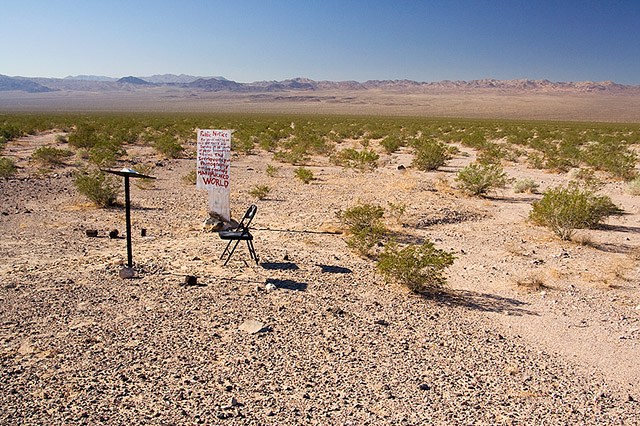 image of desert with sign, chair, and lecturn in the distance