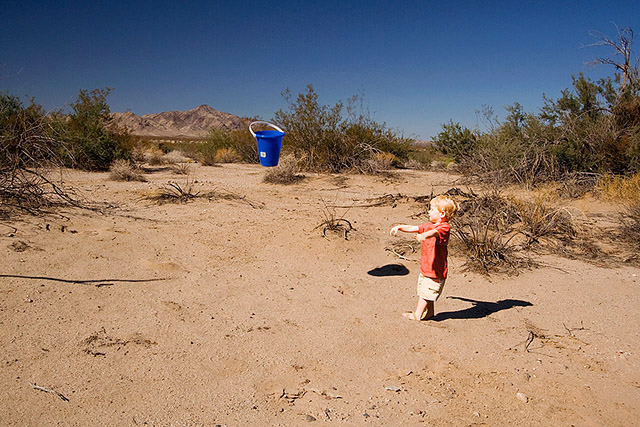 toddler throwing a bucket in the middle of the desert